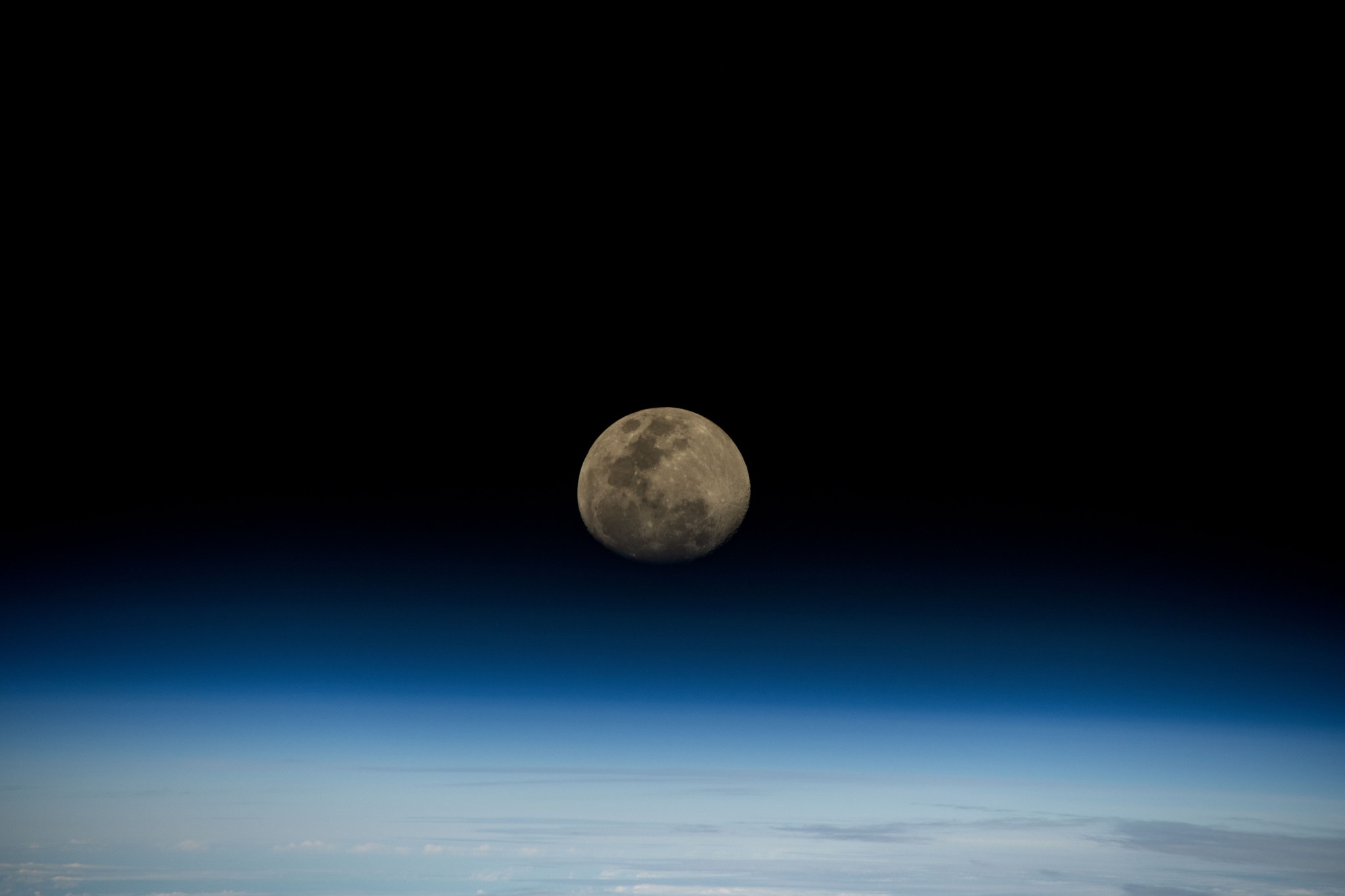 A waxing gibbous moon rises over the blue glow of Earth's horizon as the International Space Station orbited 264 miles above the Indian Ocean.