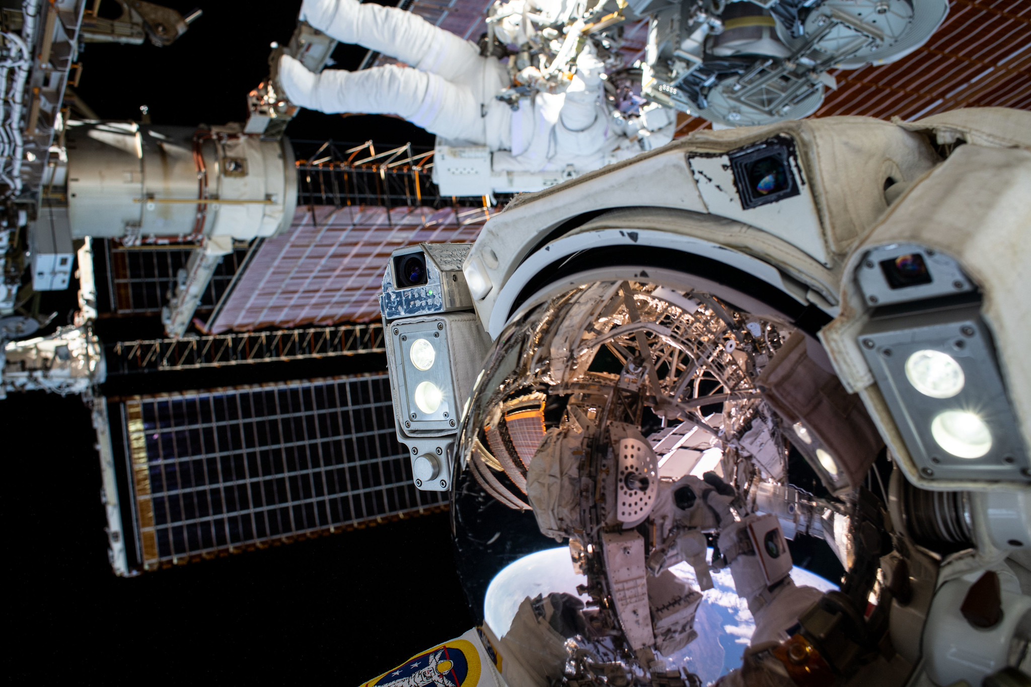 This unique "space-selfie" from spacewalker Thomas Pesquet of ESA (European Space Agency) captures he and NASA spacewalker Shane Kimbrough as they work to complete the installation of the second roll out solar array on the International Space Station's Port-6 truss structure. Pesquet is in the foreground, with his helmet facing the camera, and Kimbrough is behind and above him, floating horizontally in his spacesuit, working on the space station.