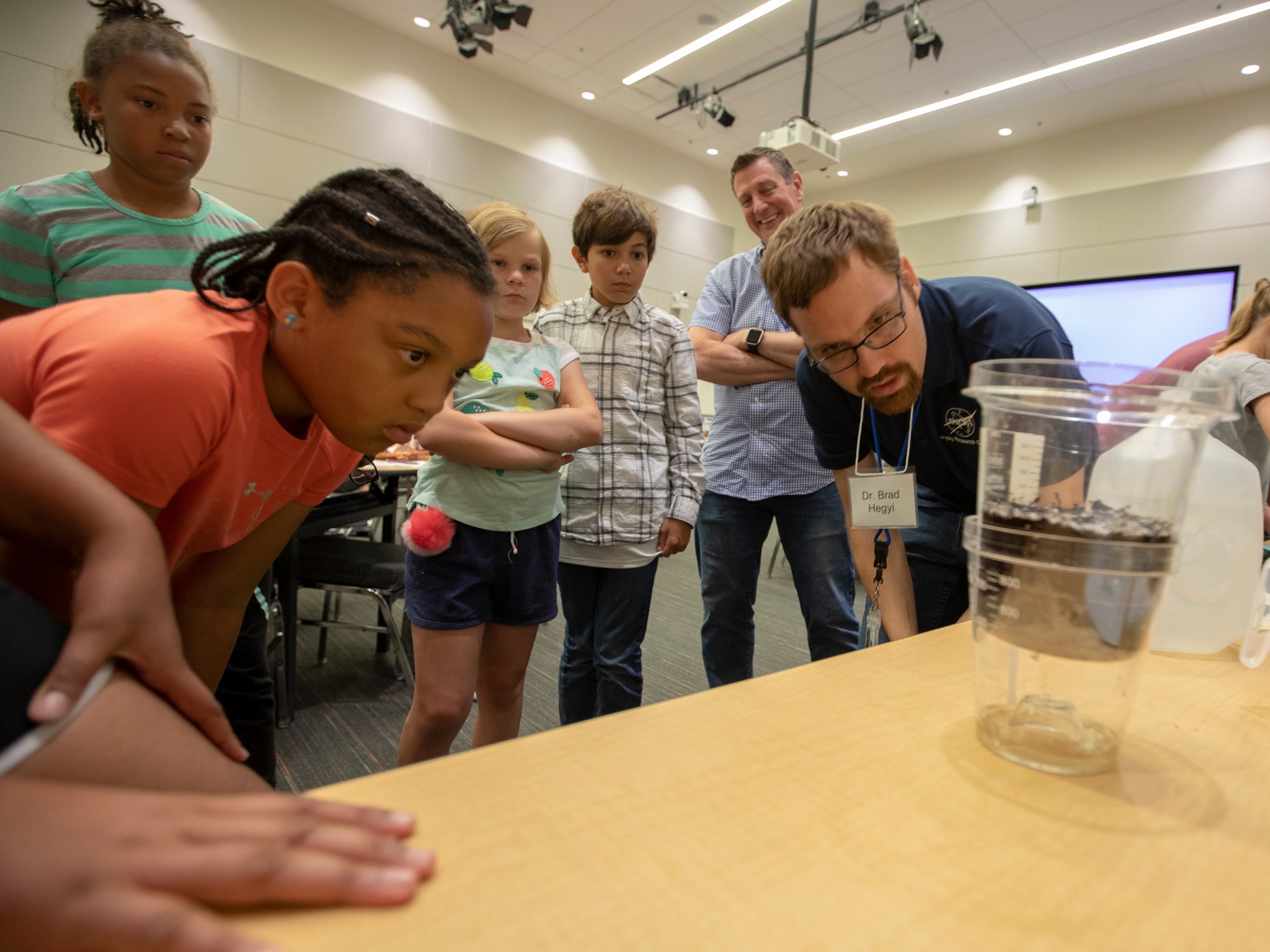 Elementary school students observe a science experiment with a NASA researcher.