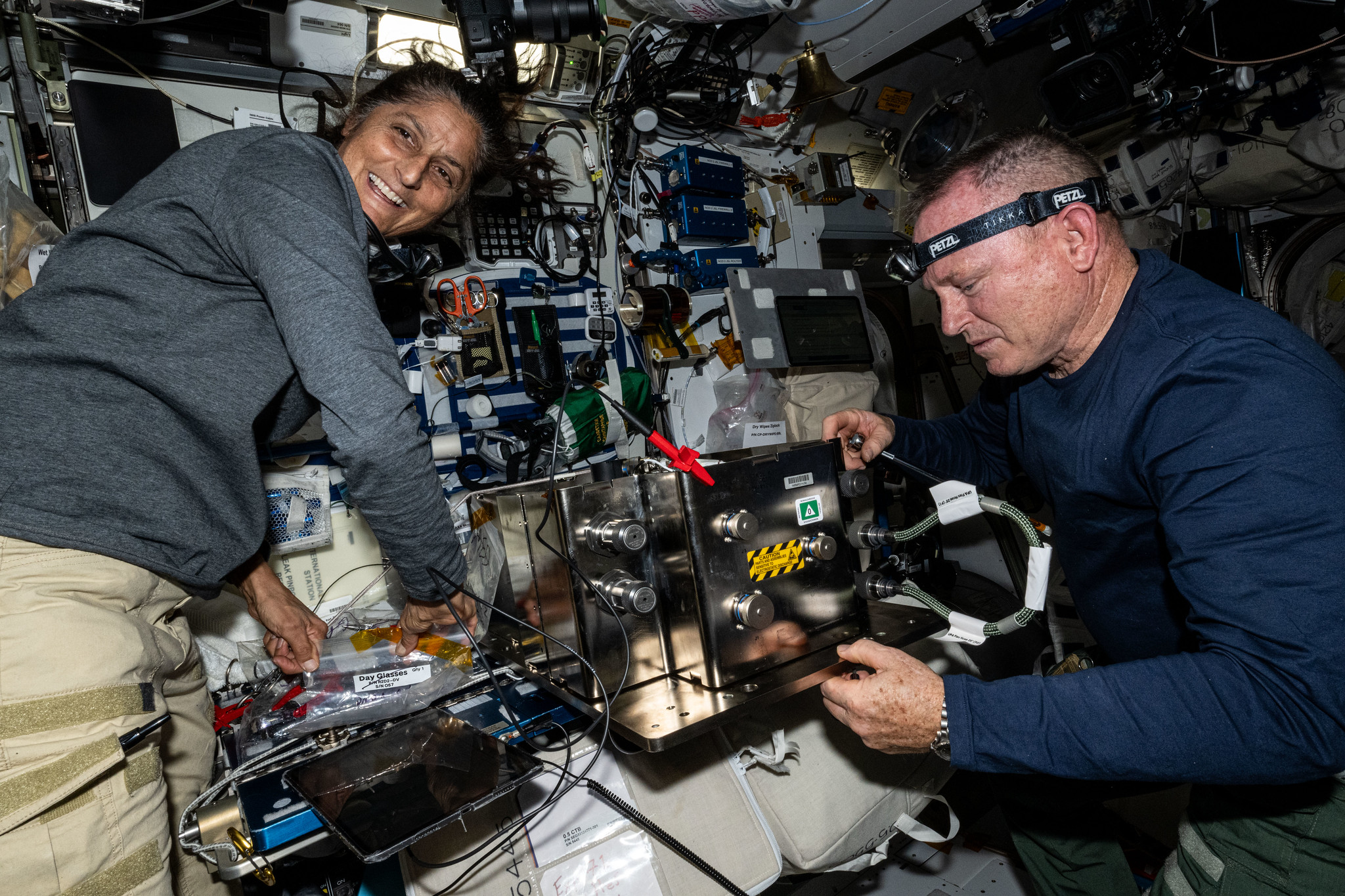 NASA astronauts Butch Wilmore and Suni Williams prepare orbital hardware for installation inside the International Space Station.