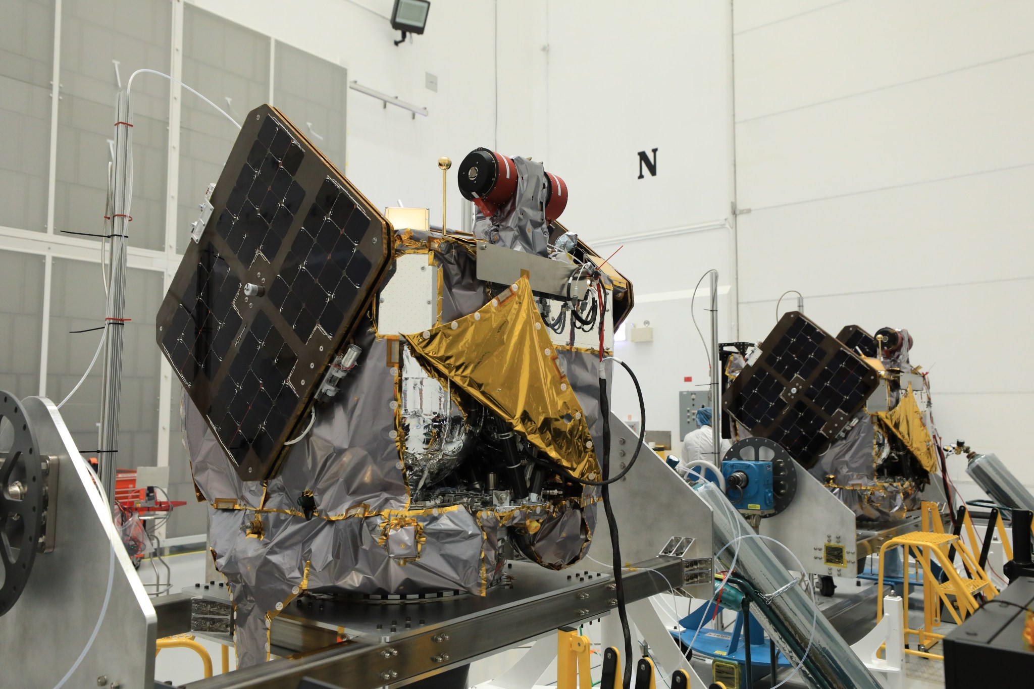 NASA’s ESCAPADE (Escape and Plasma Acceleration and Dynamics Explorers) identical dual spacecraft are inspected and processed on dollies in a high bay of the Astrotech Space Operations Facility near the agency’s Kennedy Space Center in Florida on Thursday, Aug. 22. As the first multi-spacecraft orbital science mission to Mars, ESCAPADE’s twin orbiters will take simultaneous observations from different locations around the planet and reveal the real-time response to space weather and how the Martian magnetosphere changes over time.